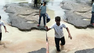 पांडव नगर पुलिस चौकी के पास कटी सड़क व पानी से गुजरता किशोर। जागरण