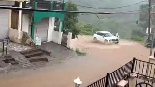 सिरमौर में भारी बारिश के कारण सड़क बहता पानी व फंसी कार। जागरण