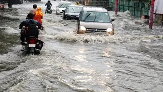 बुलंदशहर में डीएम रोड पर जलभराव के बीच गुजरते वाहन। जागरण