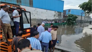 सड़क पर हुए गड्ढे में डूबे ऑटो की तलाश करती जेसीबी।