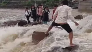 उफनते नाले को पार करते स्कूली बच्चे। (वीडियो ग्रैब)