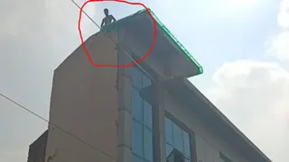 कर्मयोगी एन्क्लेव में निषाद चौक के पास बने तीन मंजिला भवन की छत पर चढ़ा युवक।
