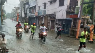 बारिश के बीच गुजरते कांवड़िये।