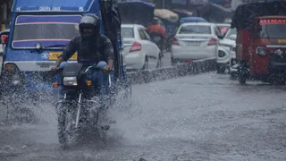 बारिश के बीच से गुजरते लोग।