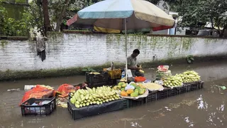 धनबाद के कोर्ट रोड में फुटपाथ पर जलभराव के बीच दुकान लगाए बैठा दुकानदार। (फोटो: अमित सिन्हा)