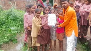 ग्राम बड़ी मड़ैया में रास्ते में हुए कीचड़ की समस्या के लिए जिलाधिकारी को लिखा पत्र दिखाते स्कूली बच्चे