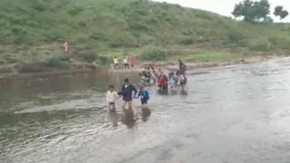 नदी से होकर गुजरते बच्चे व ग्रामीण। (फोटो- जागरण)