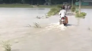 आरा के बड़हरा में जलमग्न सड़क से गुजरते लोग।