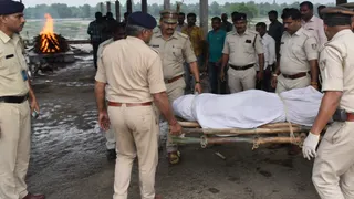 श्मशान घाट से शव ले जाती धनबाद पुलिस।(फोटो एआइ)