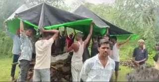 चिता को अग्नि देने के लिए तिरपाल तानकर खड़े ग्रामीण। वीडियो ग्रैब