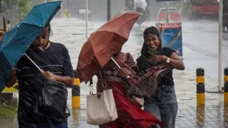 तेज बारिश और हवा के झोंकों से बचने का प्रयास करतीं युवतियां। (फाइल फोटो)