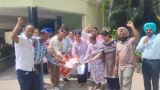 आदेशों की कॉपियां जलाते हुए कर्मचारी।