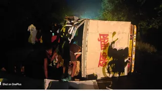 सड़क पर पलटी वैन से शराब की बोतलें निकालते लोग। (फोटो साैजन्य)