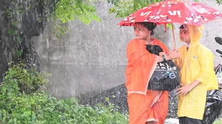 बारिश के बीच बच्चे के साथ स्कूल बस का इंतजार करती महिला। (फाइल फोटो)