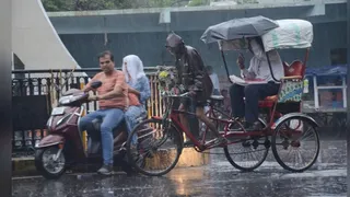 धनबाद के रणधीर वर्मा चौक पर बारिश के बीच गुजरते राहगीर। (फाइल फोटो)