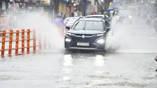 बारिश के बीच से निकलती गाड़ी।