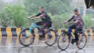 बारिश के बीच साइकिल से जातीं बालिकाएं। जागरण