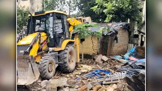 निगम की भूमि पर बने झोपड़ी को ध्वस्त करता निगम का बैकहोलोडर। जागरण