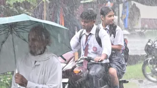 धनबाद में बारिश के बीच बाइक से स्कूल जाते छात्र-छात्रा। (फोटो मनीष)