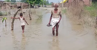बाढ़ के पानी से होकर गुजरते बुजुर्ग। जागरण