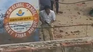 दीवार की आड़ लेकर फायरिंग करता शख्स।