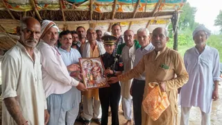 पिसावा में लेफ्टिनेंट तपस्या चौधरी को राधा-कृष्ण चित्र भेंट कर सम्मानित करते किसान