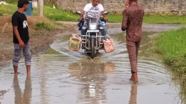बांका में जलजमाव से जनजीवन बेहाल, हाथ में जूते-चप्पल लेकर सड़क पार करने को मजबूर माहुचक गांव के लोग
