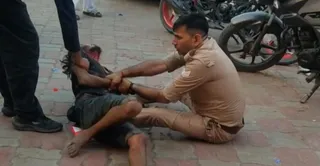 युवक को पकड़े पुलिसकर्मी। वीडियो ग्रैब