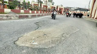गांधी समाधि पर सड़क में हुए गड्ढों से होकर गुजरते वाहन। जागरण