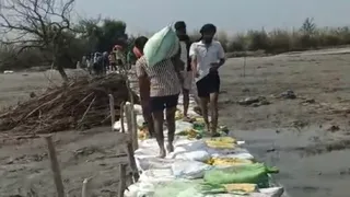 अस्थायी तटबंध तैयार करते ग्रामीण।