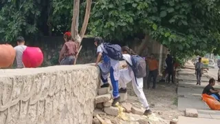 दीवार फांदकर जाते बच्चे।