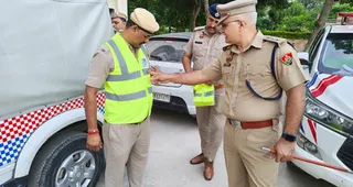 पुलिसकर्मी रिफ्लेक्टर जैकेट का महत्व बताते एसीपी सुरेन्द्र सिंह।