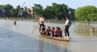 राप्ती नदी में आयी बाढ़ के पानी से घिरे नौसढ़ के पास स्थित बहरामपुर उत्तरी के ग्रामवासी नाव का सहारा लेकर घर को जाते हुए। पंकज श्रीवास्तव