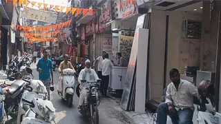सदर बाजार की मुख्य सड़क पर आधे रास्ते में खड़े वाहन, आधे से गुजरते बाइक सवार और राहगीर। जागरण।