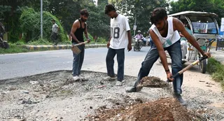 रेल म्युजियम से सटे रेलवे स्टेशन पर जाने वाले मार्ग के गड्ढे भरते युवा। जागरण