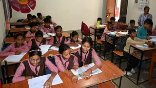 मथुरा के स्कूल में कुछ बच्चे बिना यूनिफार्म ही बैठे हैं।