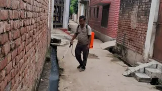 शहर की गली में एंटी लार्वा स्प्रे का छिड़काव करता कर्मचारी।
