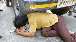 पुलिस जीप के पहिए के आगे बच्चे को रखता युवक। वीडियो ग्रैब