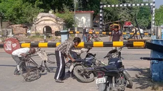 शाहजहांपुर में मोक्षधाम सड़क पर बंद रेलवे क्रासिंग से बाइक निकालते लोग। जागरण