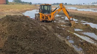 किऊल नदी के तट पर छठ घाट की सफाई और समतलीकरण करते मशीन