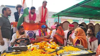छाता में पैरा एशियन गेम्स में रजत पदक विजेता राम रतन सिंह जादौन का स्वागत करते स्थानीय लोग। फोटो जागरण