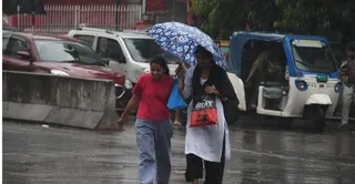 बड़ा चौराहा पर वर्षा में जातीं युवतियां । जागरण