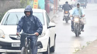 बारिश के बीच गुजरते लोग।