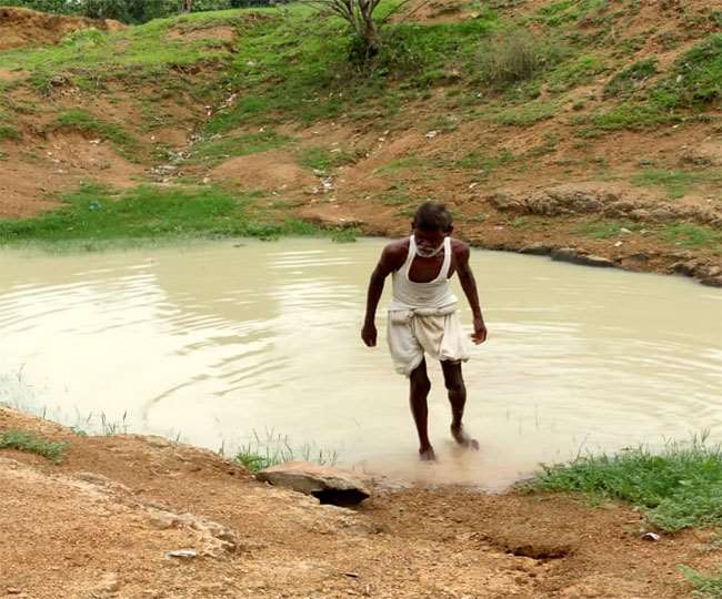 Jharkhand Dhanbad News खोदे गए तालाब के पास खड़े भोलानाथ। जागरण
