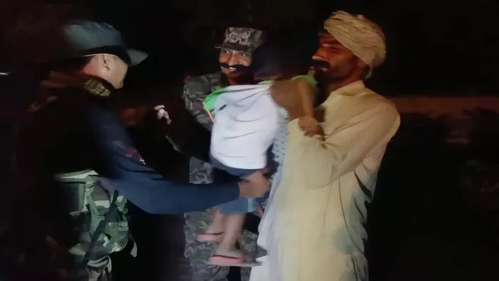 बच्चे को परिवार के हवाले करते हुए बीएसएफ अधिकारी। (जागरण)
