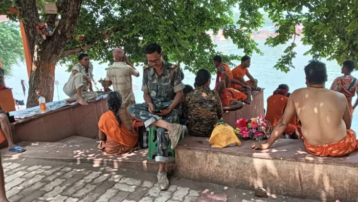 बुधवार को शिवगंगा तट स्थित मस्जिद के सामने बैठकर मोबाइल देखते पुलिसकर्मी। फोटो- जागरण