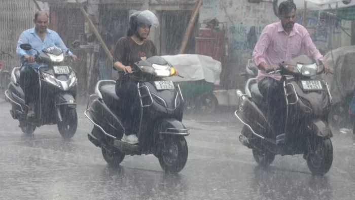 बारिश के बीच से गुजरते राहगीरों के वाहन। जारगण फाइल