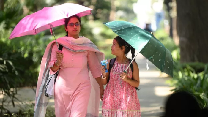 तेज धूप से बचने के लिए छाता लगाकर बच्ची के साथ गुजरती महिला। फाइल फोटो- जागरण