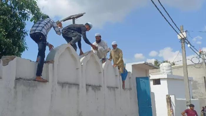 संभल के राया बुजुर्ग में मस्जिद की दीवार तोड़ते लोग। जागरण