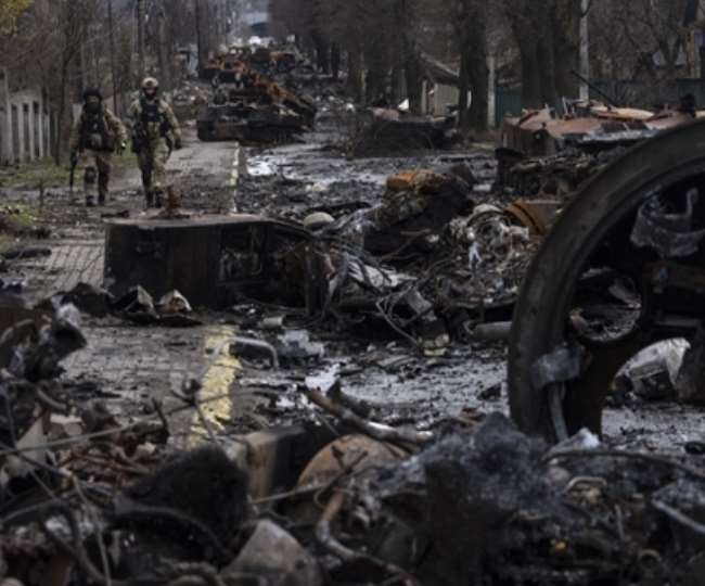 बुचा में नष्ट हुए रूसी टैंकों के बीच से गुजरते यूक्रेनी सेना के जवान (Photo AP)